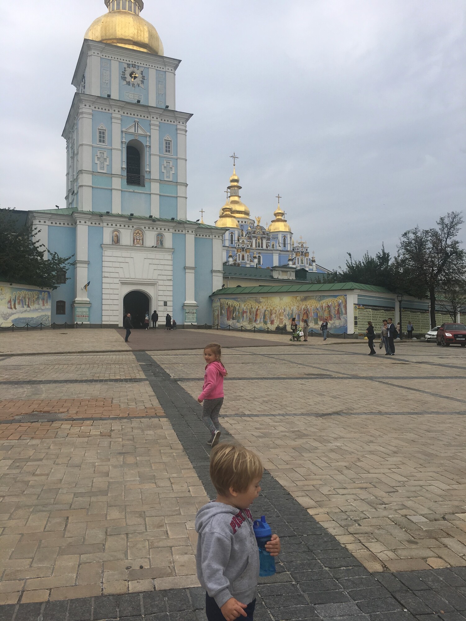 Two children candidly standing in front of St. Michael’s Golden-Domed Monastery in Kyiv, Ukraine
